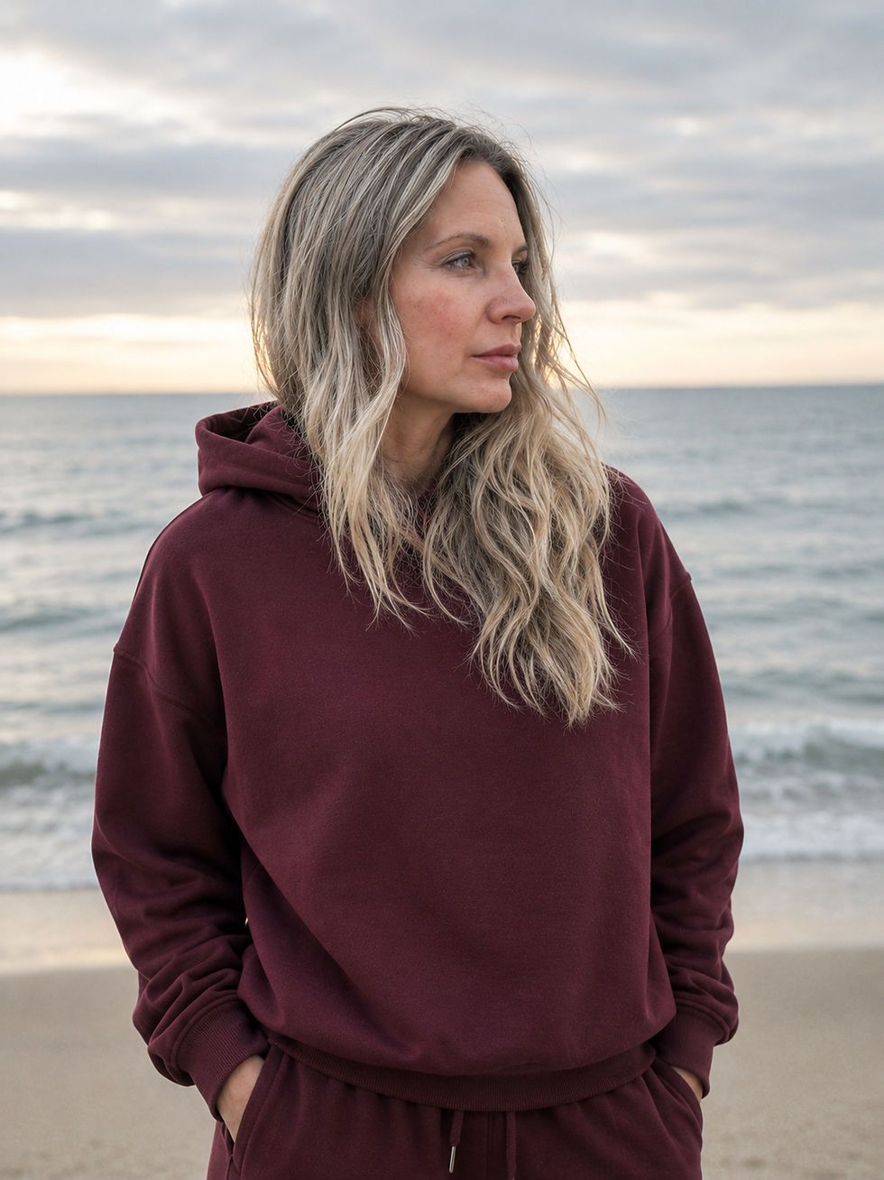 Woman wearing Canadian Huntress burgundy hoodie outdoors by the water