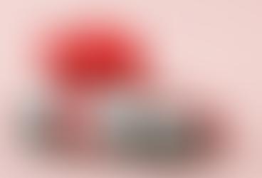 A white SUV wrapped in a bright red holiday bow against a soft pink background, suggesting holiday car shopping