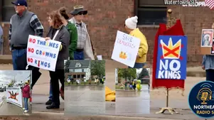 People protest in Watertown, SD, holding signs saying "No Thrones No Crowns No Kings" and "Save Democracy." A mood of determination.