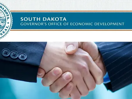 Handshake with suited arms in focus, featuring the South Dakota Governor's Office of Economic Development text and state seal, calm mood.