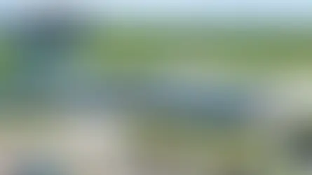 Aerial view of Watertown Regional Airport with parked cars, green fields, and "Fly ATY" text overlay. Bright, clear day.