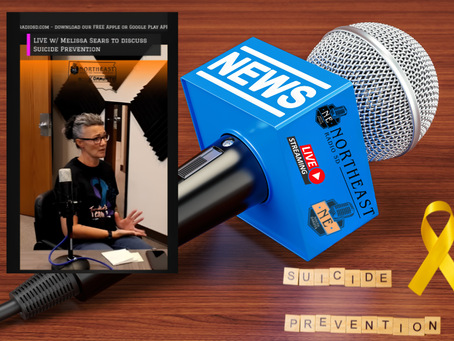 Woman speaks on a live radio/podcast about suicide prevention, beside a blue NEWS mic and yellow ribbon on a wood table.