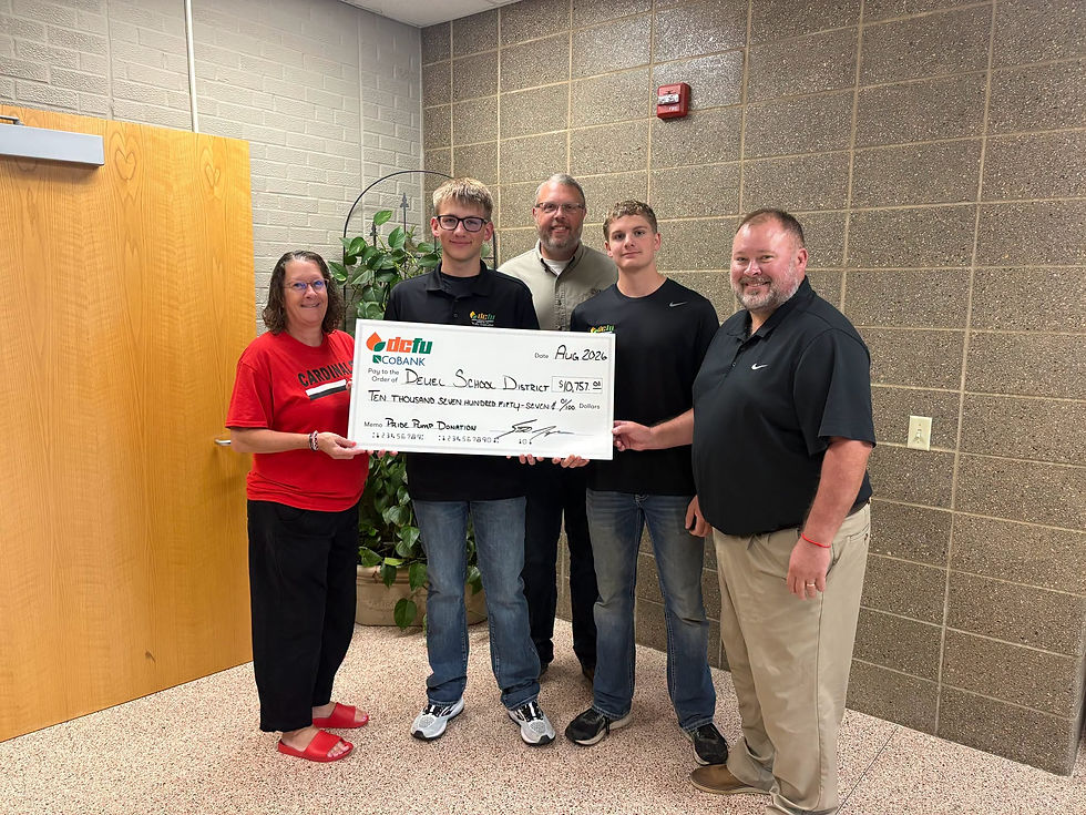 Five adults smile in a hallway holding a large check for Deuel School District, marked Pride Pump Donation.
