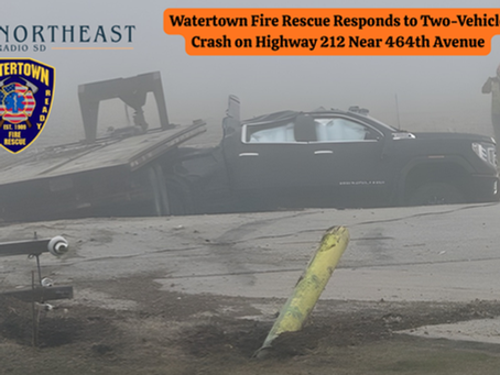 Damaged black truck in foggy crash scene on Highway 212. Person photographing. Text: "Watertown Fire Rescue Responds to Two-Vehicle Crash."