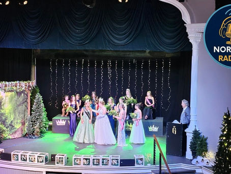 Girls in gowns hold bouquets on stage with "Snow Queen" banner, trees, and twinkling lights. A man stands at a podium. Festive mood.