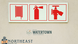 Red fire safety icons for radiator, extinguisher, and hose valve on a wall, with Watertown, South Dakota and Northeast Radio SD logos.