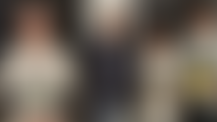 Young woman holding a "Volunteer of the Year" plaque, smiling with two men. Wearing casual clothes, indoors, with awards featuring Lakers logo.