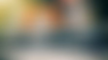 Workers in orange gear paving a road with asphalt under sunlight. A Northeast Radio SD logo in the corner. Warm, busy scene.