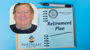 Notepad on blue surface with "Retirement Plan" text, Codington County seal, and a smiling person. Pen and Northeast Radio SD logo visible.