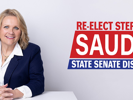 Blonde woman in a blue suit smiles at a desk. Text: "Re-elect Steph Sauder, State Senate District 4" in red and blue. White background.