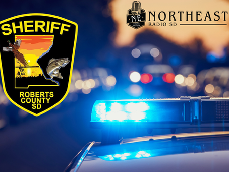 Roberts County sheriff badge beside a flashing blue patrol light; Northeast Radio SD logo over blurred police cars at dusk.