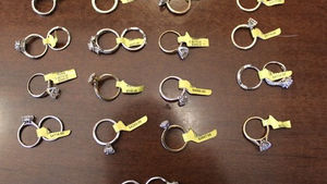 Assorted silver rings with yellow price tags arranged on a brown tabletop, suggesting a jewelry display.