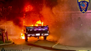 Ford pickup engulfed in flames and smoke on a street at night, with Watertown Fire Rescue and Northeast Radio SD logos visible.