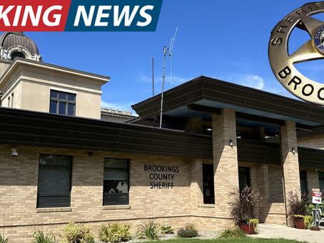 Brookings County Sheriff building under blue sky with a sheriff's badge overlay. "Breaking News" text in red and blue at the top.