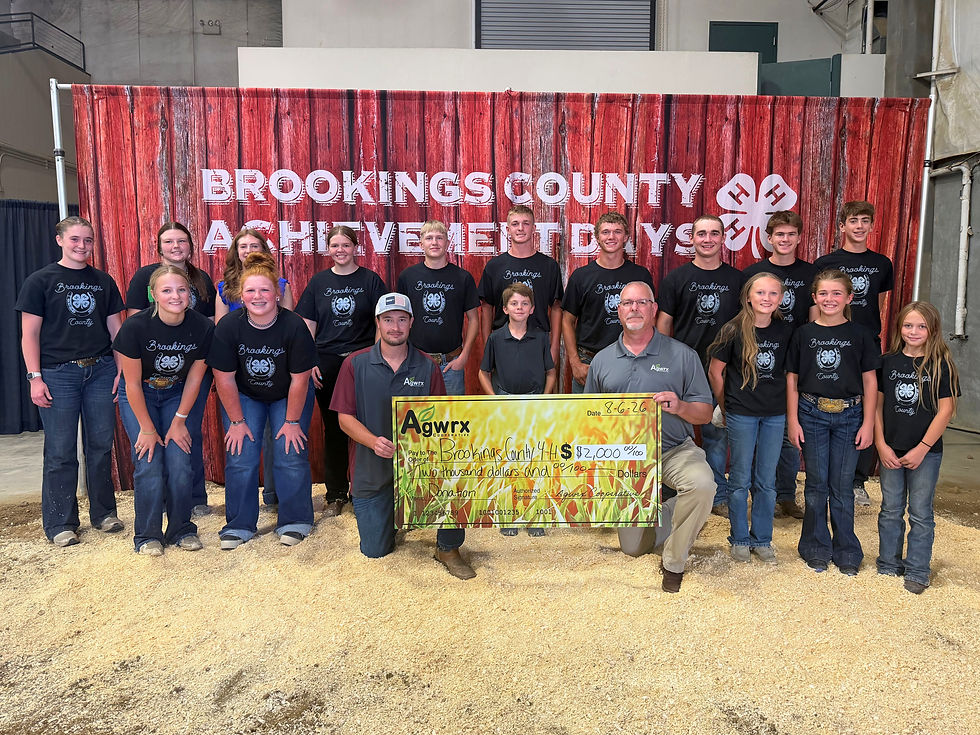 Group of 4-H youths and adults pose with a $2,000 Agwrx check in front of a Brookings County Achievement Days banner.