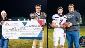 Two football players on a field, one holding a scholarship check, the other with a football. Night setting, positive mood.