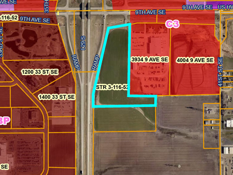 Aerial parcel map with red-shaded lots, cyan outline around green field, and labels like 9TH AVE SE, US HWY 212, and STR 3-116-52.
