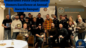 Police officers at awards banquet holding plaques, posing in a decorated room with "Watertown Police Department Honors Excellence" text.