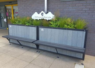 A planter drainage system with seating is pictured in front of  a grey wall