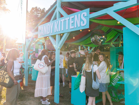 People gathered at a colorful outdoor festival stand.