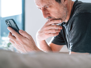 Middle-aged man looking worried while staring at his smartphone.