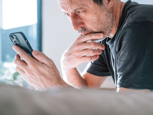 Middle-aged man looking worried while staring at his smartphone.