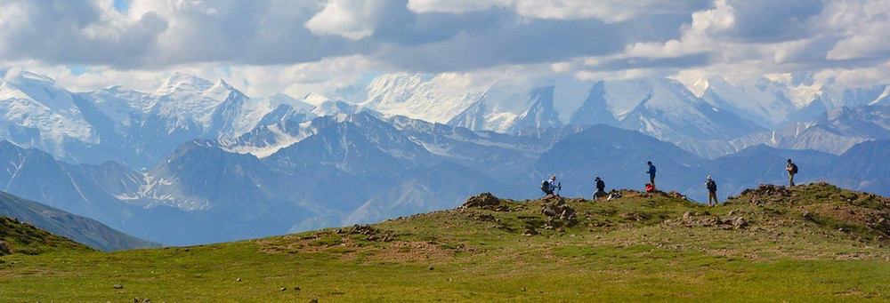Composers and naturalists hike in silhouette through Denali National Park, against a backdrop of the mountains of the Alaska Range. Photo provided by Stephen Lias for Composing in the Wilderness.
