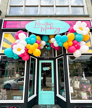Yellow, teal, and pink balloon garland on front of business