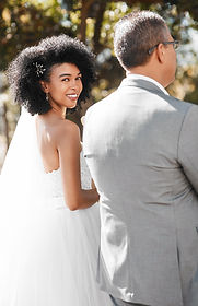 Smiling bride in strapless wedding gown with veil sharing a joyful moment during outdoor wedding ceremony