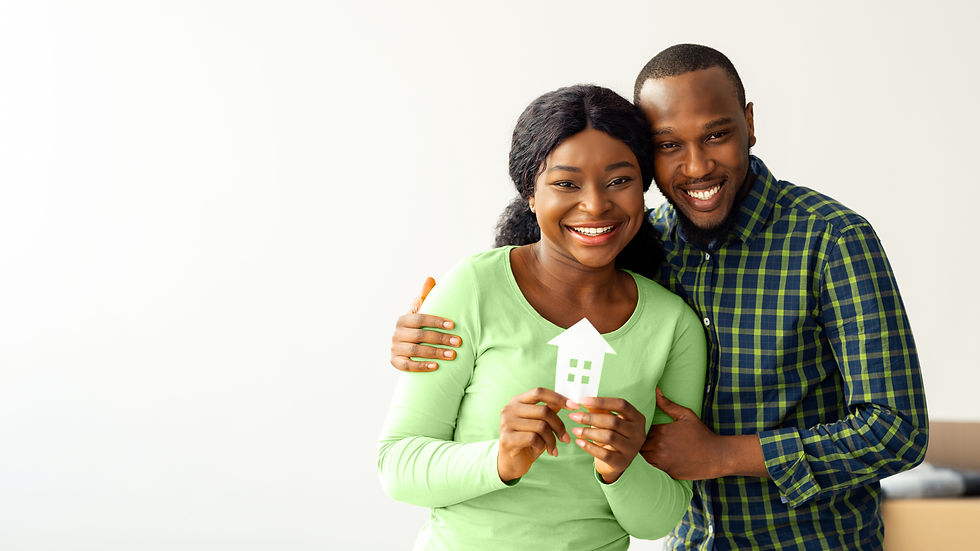 A joyful African-American couple holds a paper cutout of a house, symbolizing their excitement about homeownership and real estate opportunities.