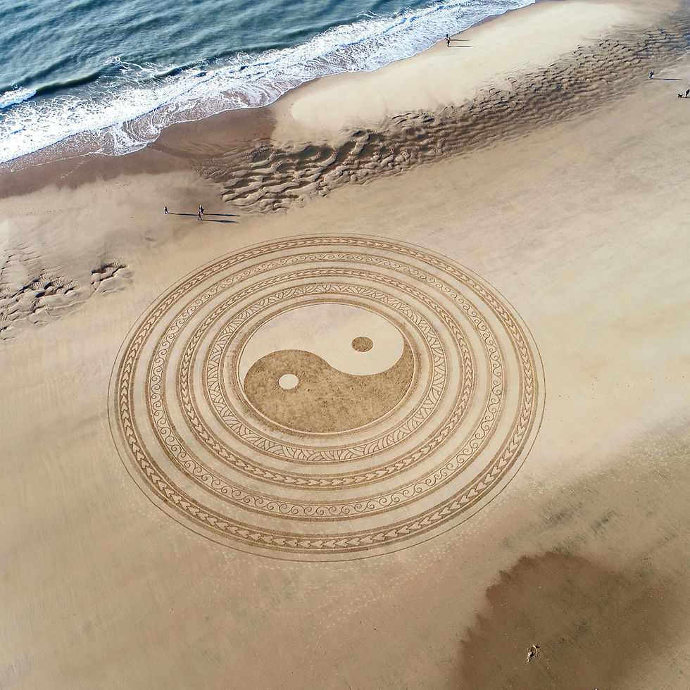 stort motiv af Yin og Yang tegnet i sandet en solskins dag på stranden