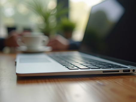 Eye-level view of a sleek laptop on a wooden desk with a coffee cup