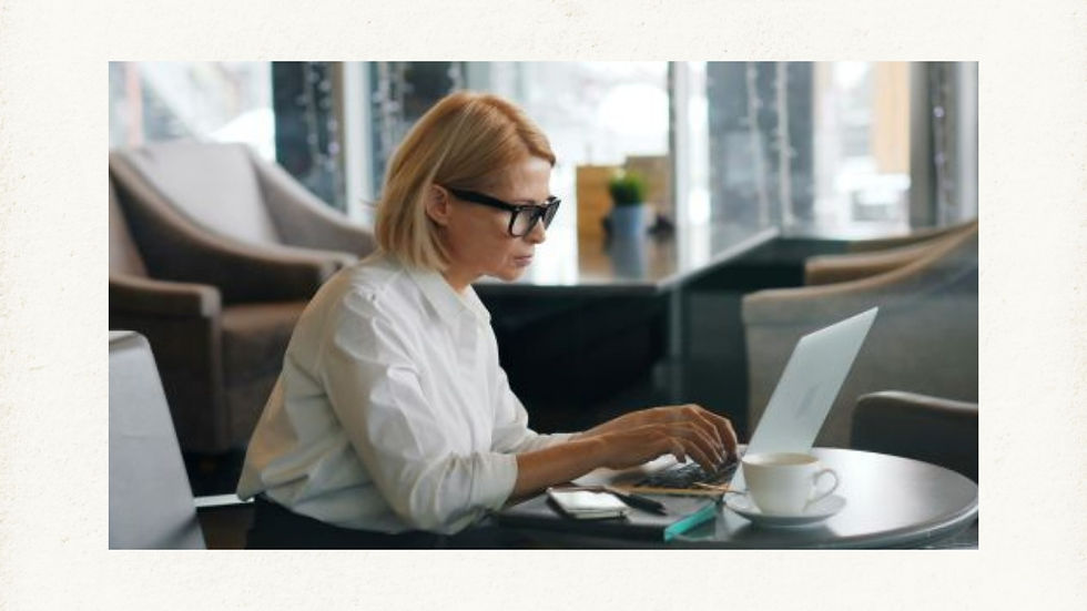 Woman using one of the best laptops for content creators in a modern café, typing with focus beside a cup of coffee.