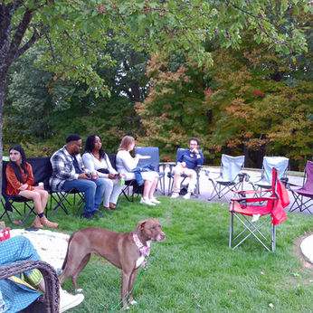 People sitting in chairs outdoors with a dog