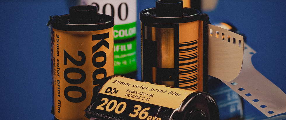 Vintage 35mm film rolls with visible text "Kodak 200" and "35mm color print film". Bright background, blue surface, nostalgic mood.