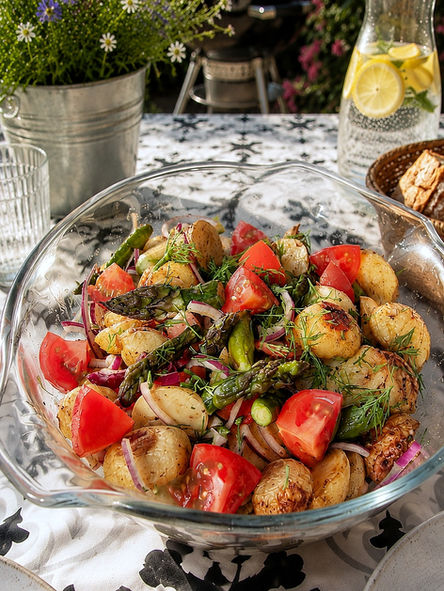 Vegetarischer Ofenkartoffelsalat mit knusprigen Ofenkartoffeln, grünem Spargel, Tomaten und roten Zwiebeln in einer großen Schüssel serviert – perfekt als sommerliche Grillbeilage.