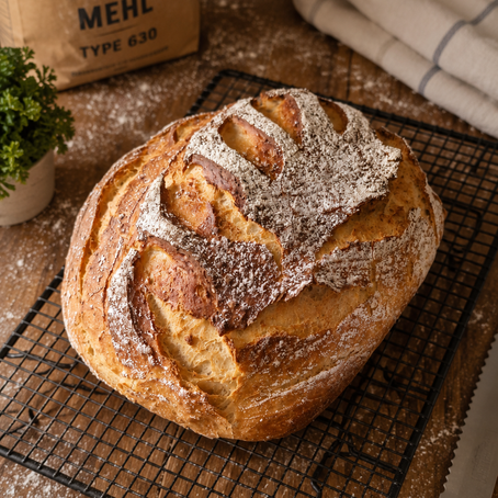Frisch gebackenes saftiges Dinkel-Joghurtbrot aus dem Pampered Chef Ofenmeister mit knuspriger Kruste und weicher Krume auf einem Holzbrett angerichtet.