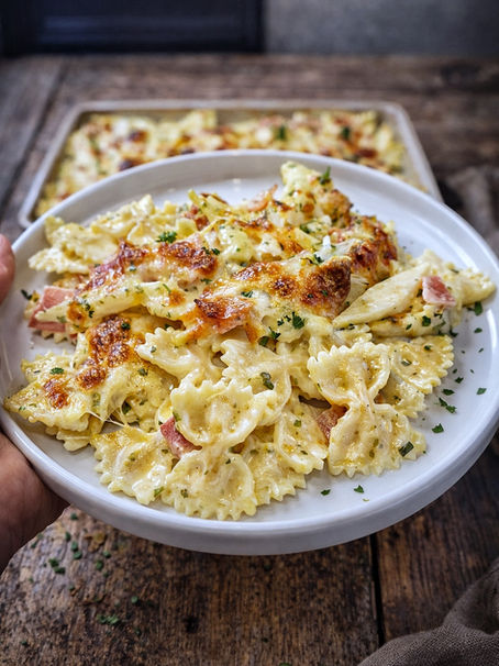 Cremige Spargelpasta mit Farfalle, grünem und weißem Spargel, Schinken, Sauce Hollandaise und geschmolzenem Mozzarella, goldbraun im Ofen gebacken.