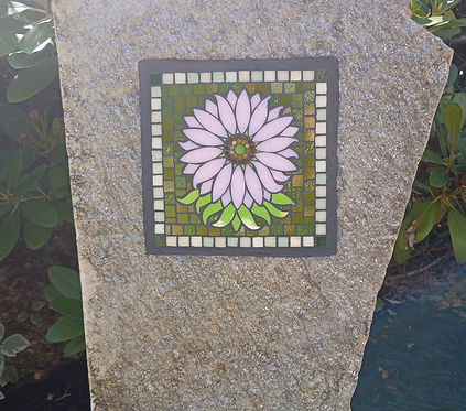 Monolith stone with a tile mosaic  daisy inlaid into the stone 