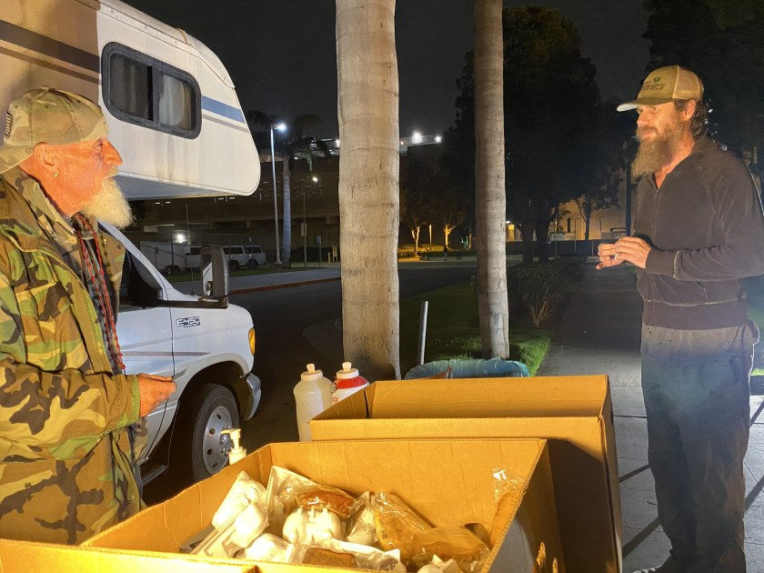 Vaskin Koshkerian, left, of the volunteer group Micah’s Way talks to Matthew Jacobs minutes after Jacobs was released from the Central Jail Complex in Santa Ana on Wednesday, Nov. 18, 2020. Koshkerian works to be a resource for newly released inmates, offering a phone, coffee, snacks and information. “I can’t save everybody. But if I save one, two people a night, that’s a success,” he said.