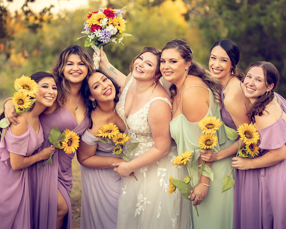 A bride and her bridesmaids embrace and pose for the camera