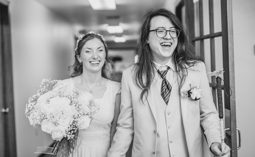 black and white photo of the bride and groom as they enter the luncheon, they laugh and smile