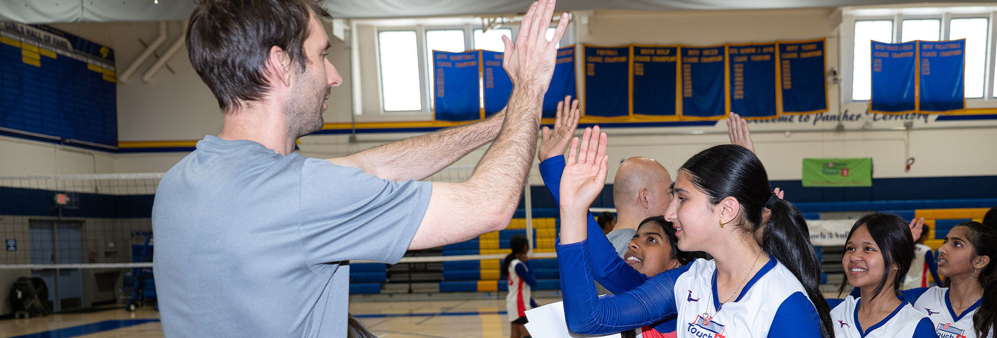 Coach high-fiving players in a youth in girls club team.