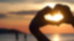 Hands making a heart shape with the sun in the background