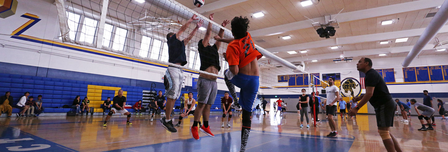 Participants at a adult volleyball game in a gym.