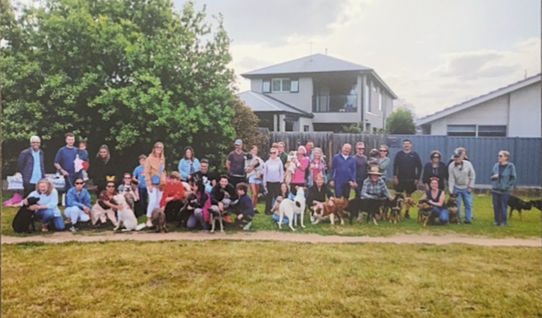 Dog owners and their dogs gathered for a group photo on the grass at Bradshaw Street Reserve, Essendon.