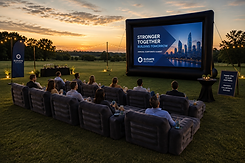 Luxury outdoor corporate event by PhotoChe Events featuring a giant inflatable movie screen, premium inflatable lounge seating, and an open-field presentation setup ideal for employee appreciation events, company movie nights, corporate retreats, product launches, team-building activities, and outdoor business presentations.