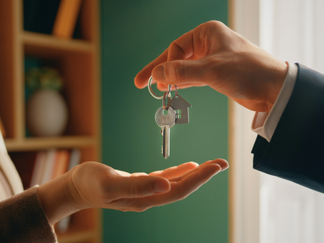 Male hand dangling keychain with key and house-shaped metal over female cupped hand