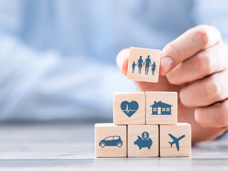 Hand stacking small cubes with icon images of different types of insurance, etc. in a pyramid