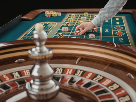 Blurred roulette wheel with hand placing bet with chips on table behind it
